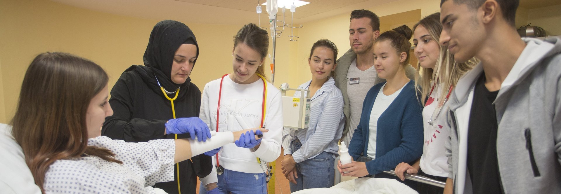 Schüler mit Patientin in Lehrsituation am Krankenbett 