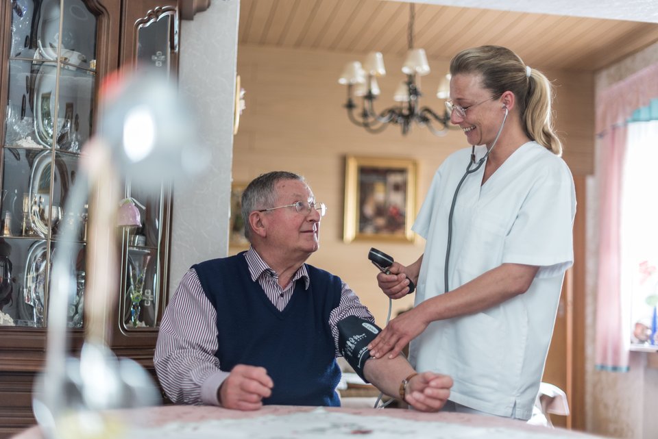 Patient bekommt daheim von Pflegerin Blutdruck gemessen